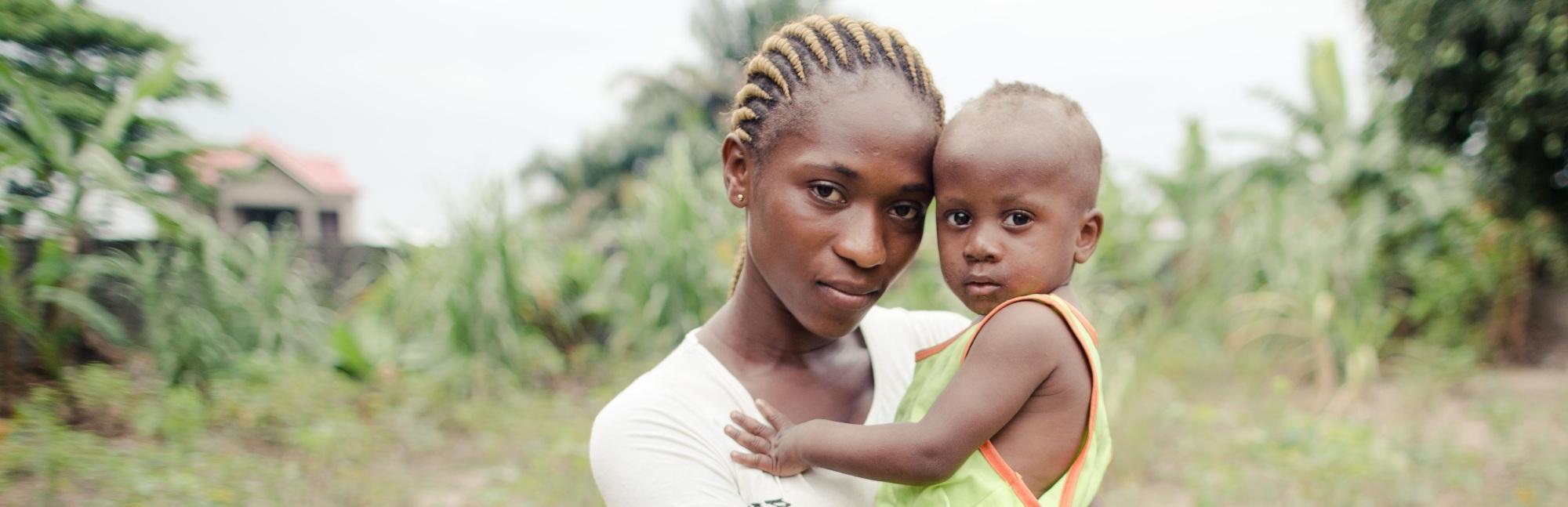 A mother holds her young African child, who suffered with pneumonia but was helped to recover, near a road in the Democratic republic of Congo.